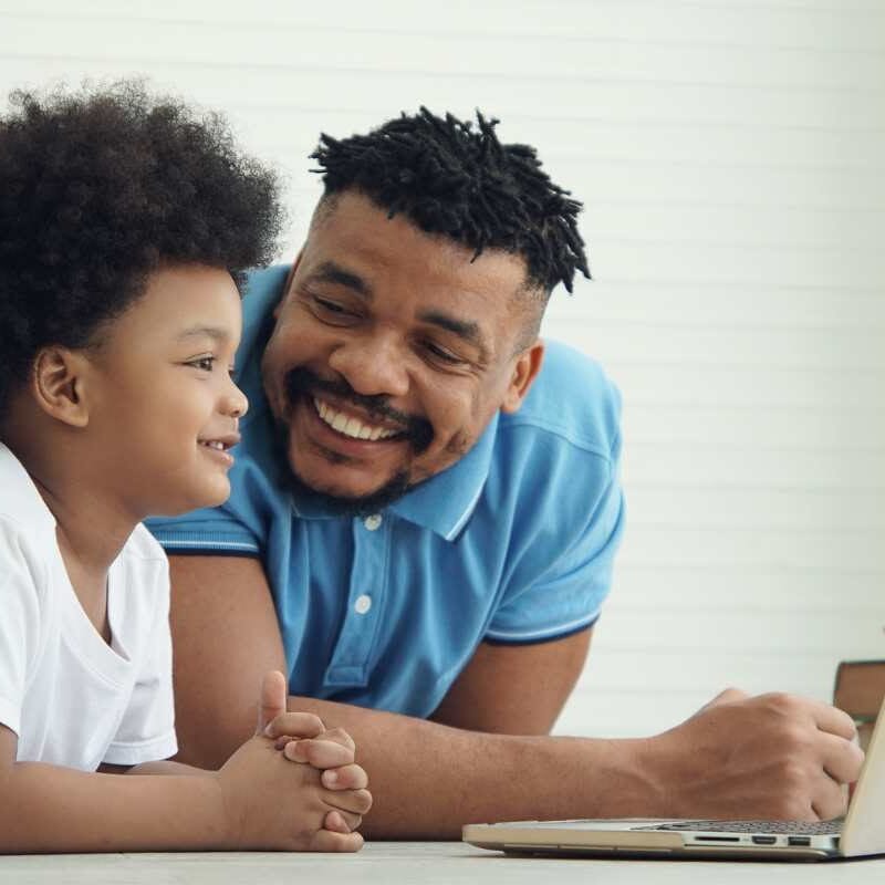 Pai no laptop com criança por perto