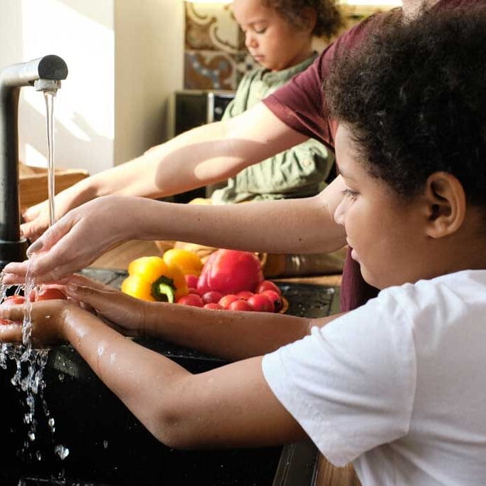 família lavando as mãos com água