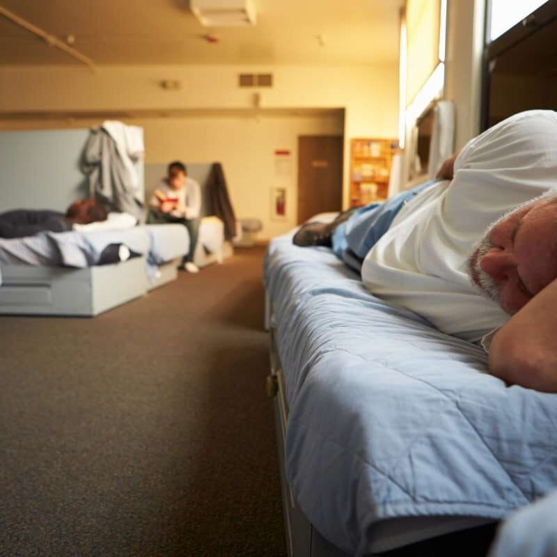 Homem deitado na cama em abrigo para moradores de rua