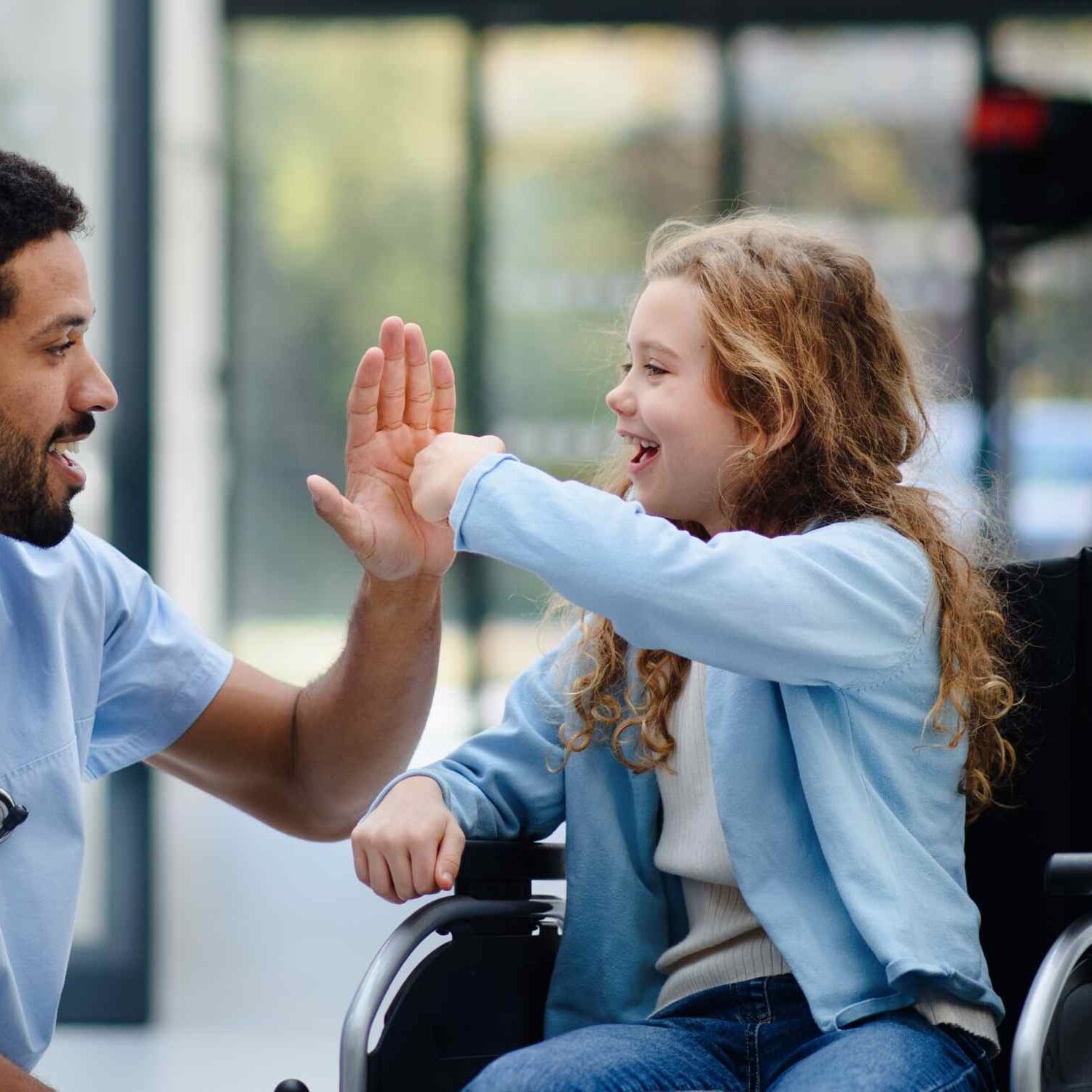 Menina em cadeira de rodas cumprimentando médico com um "high five".